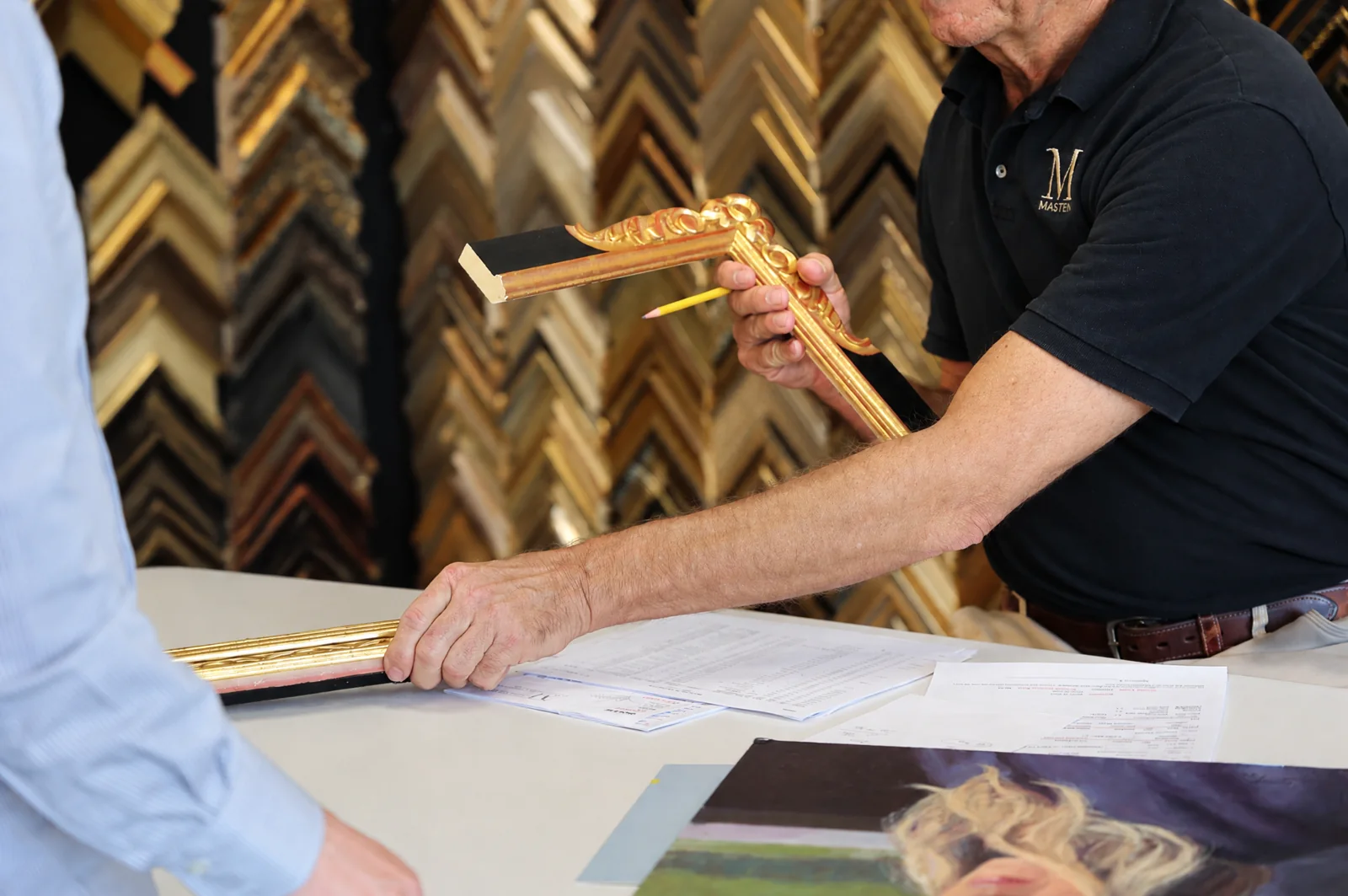 A framing professional showing moulding and artwork options during a studio consultation